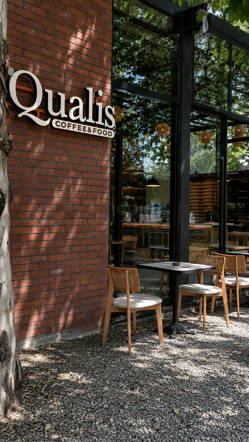 Qualis'in tuğla cephesi, tabelası ve ağaç gölgesindeki teras masaları